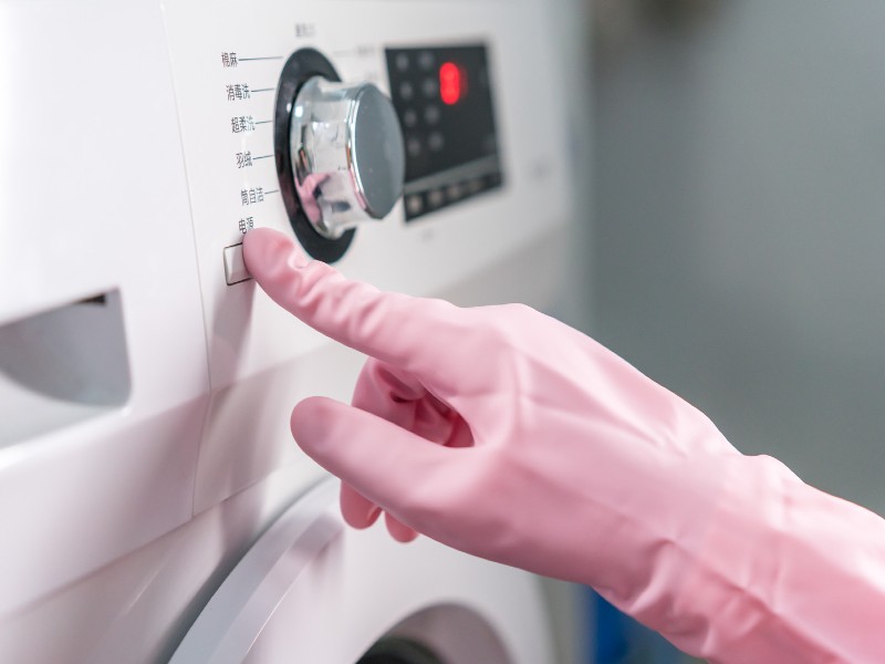Γάντι χεριών πατάει κουμπί σε πλυντήριο